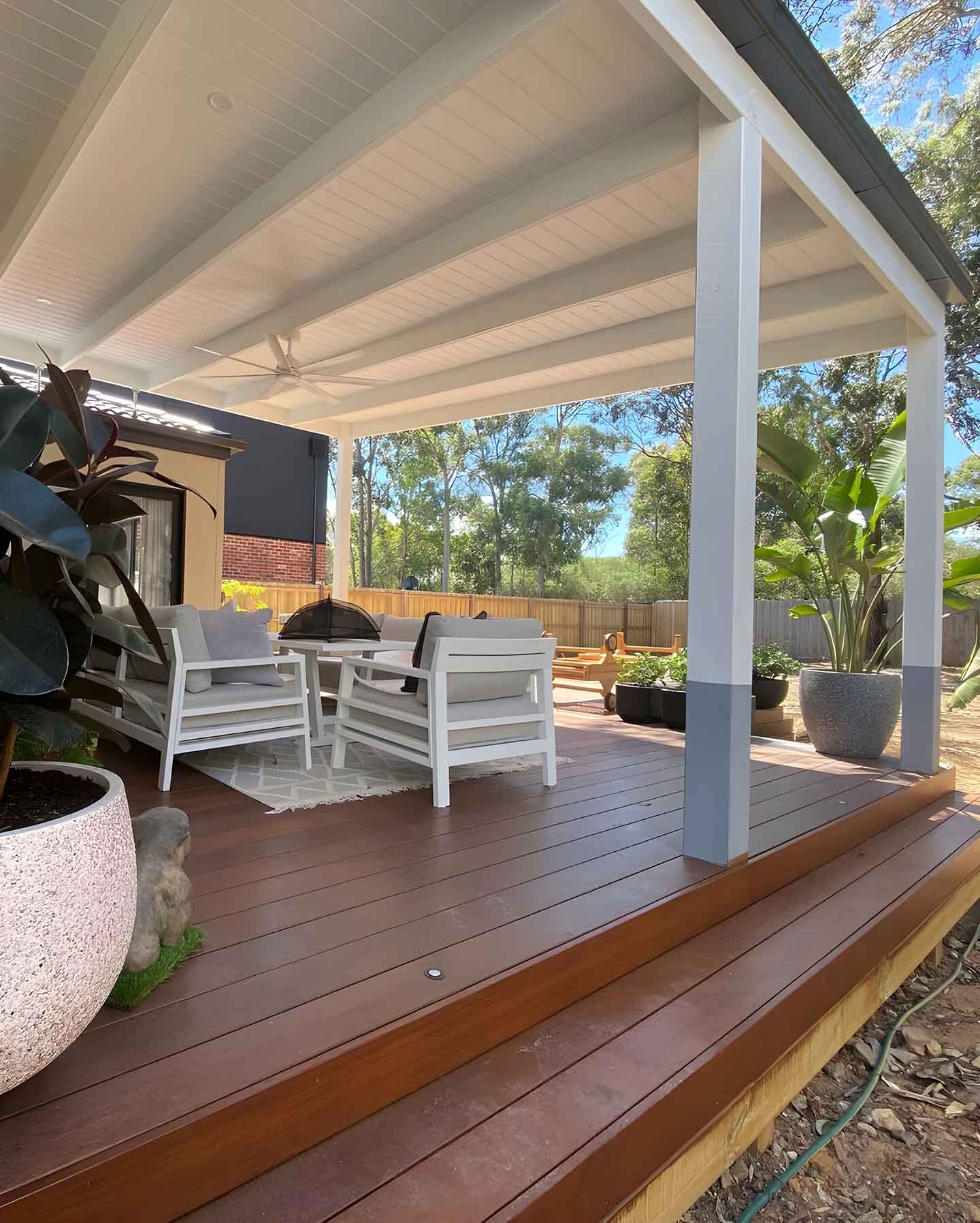 25 Covered timber deck with white posts, outdoor chairs and pot plants